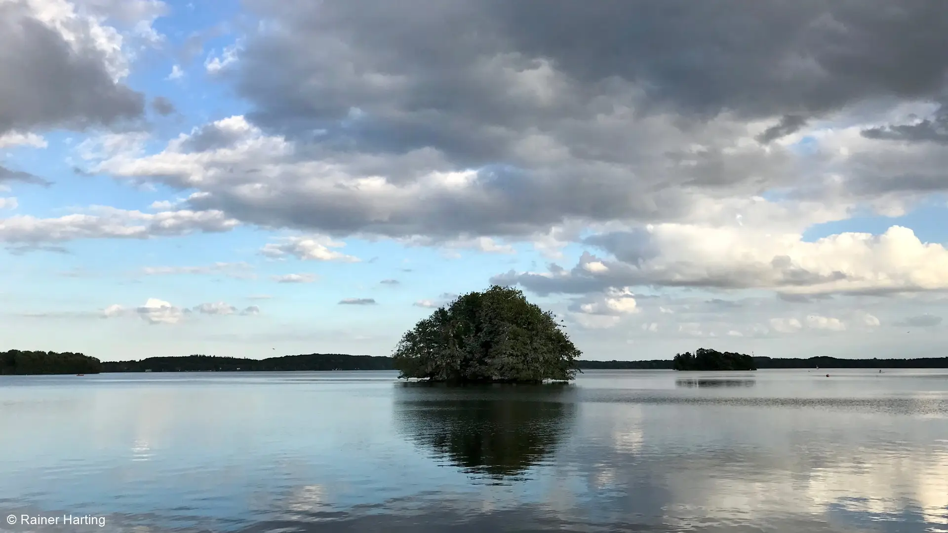Der Große Plöner See mit einer bewaldeten Insel unter Wolken